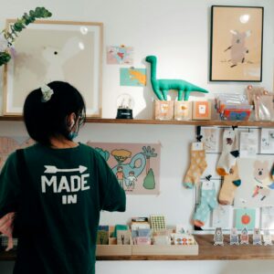 A vibrant interior of a gift shop displaying toys, socks, and wall decor, with a person browsing items.