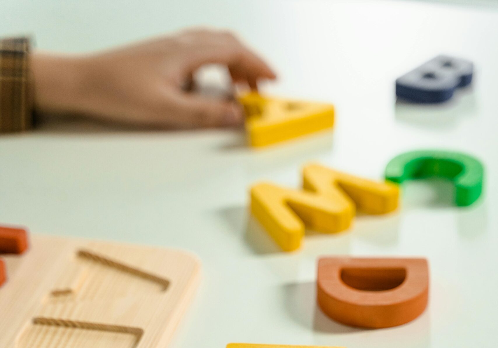 Colorful wooden alphabet letters scattered on a white surface for educational activities.