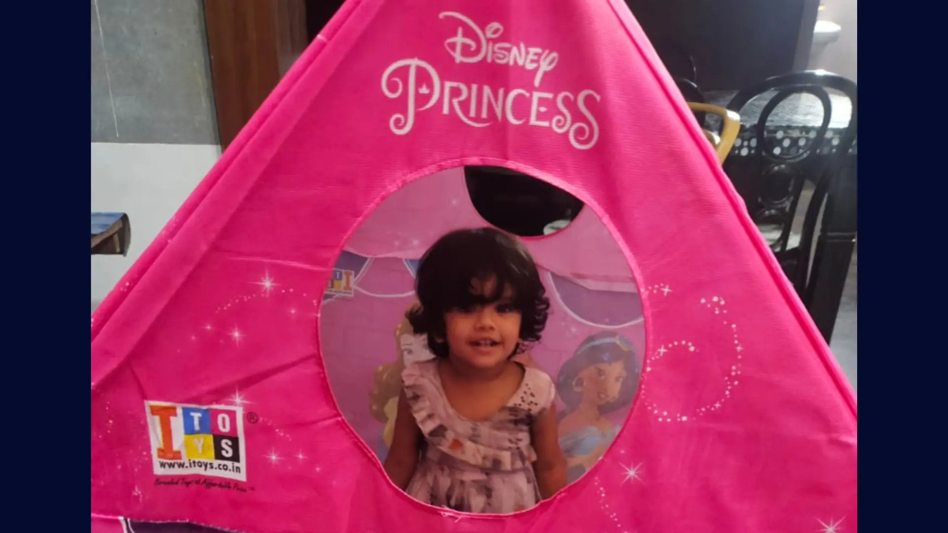 Little girl happily playing inside her pink princess tent