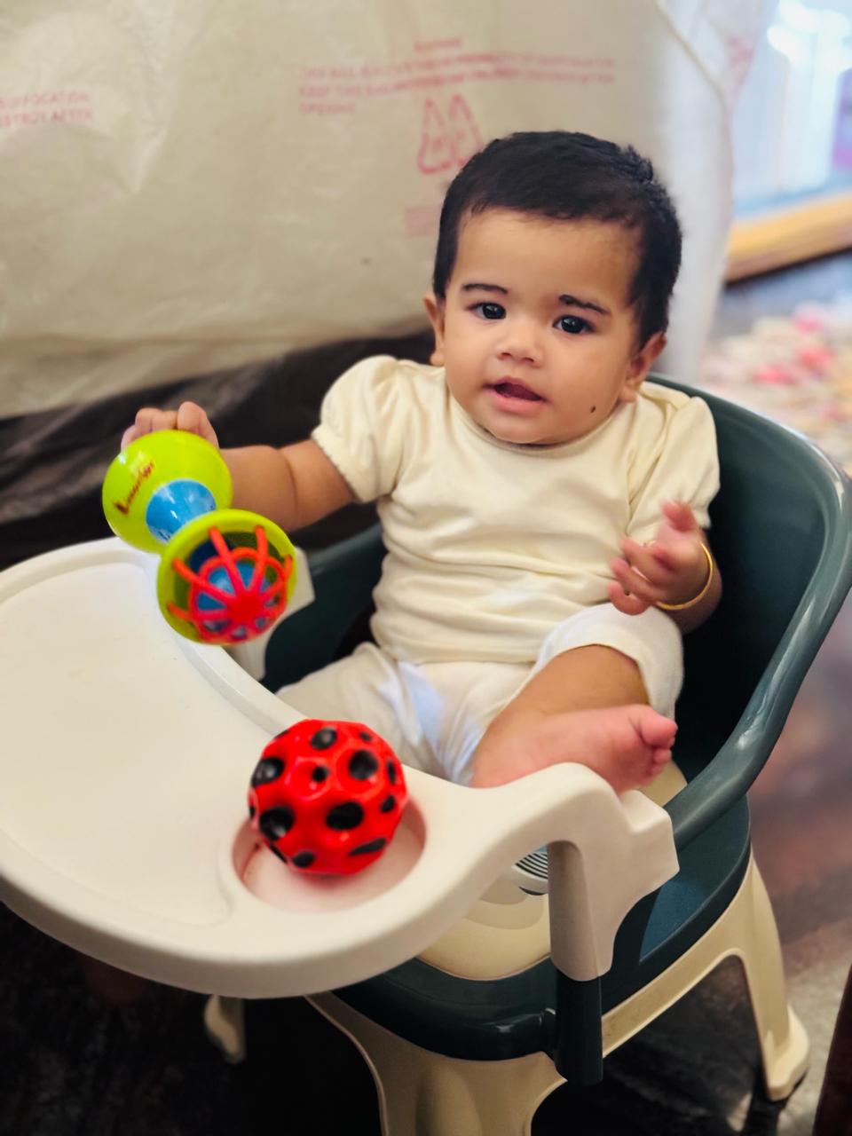 Baby exploring colourful sensory toys while sitting in a high chair