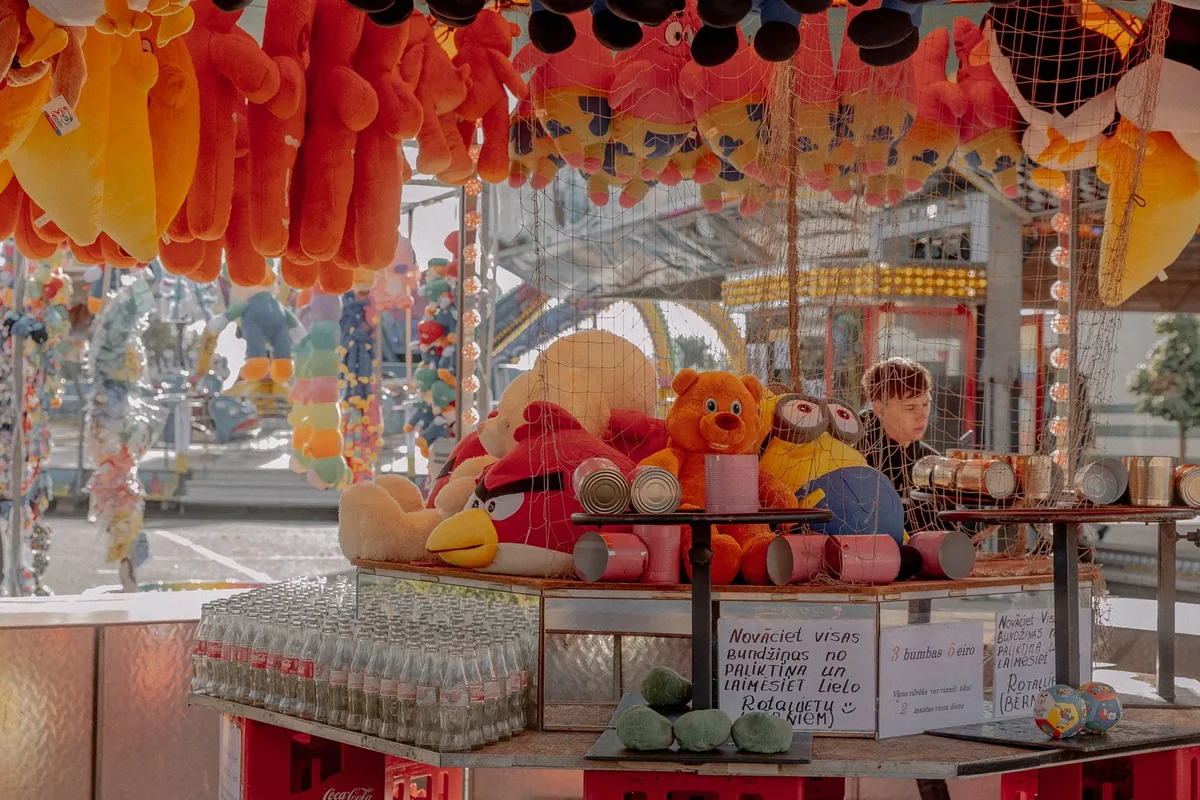 Large stuffed toy prizes, including an Angry Birds plush and teddy bears, hanging above a carnival game stall