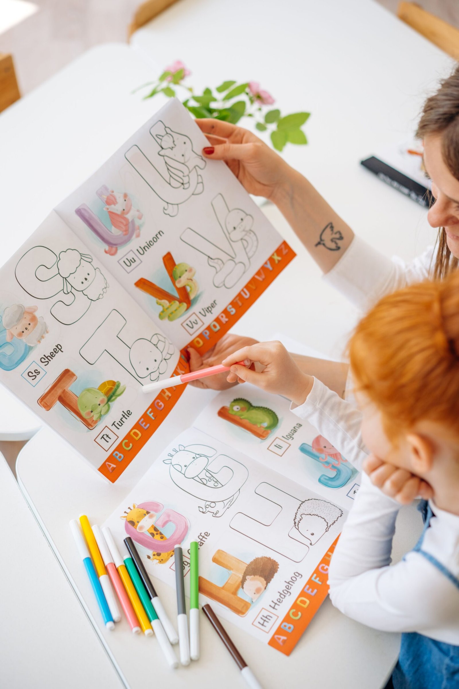2 Year Olds Books alphabet tracing page with animal illustrations being coloured by a parent and child