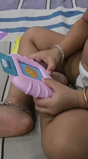  Toddler sitting on a mat holding a pink card reader toy with a blue flash card in the slot